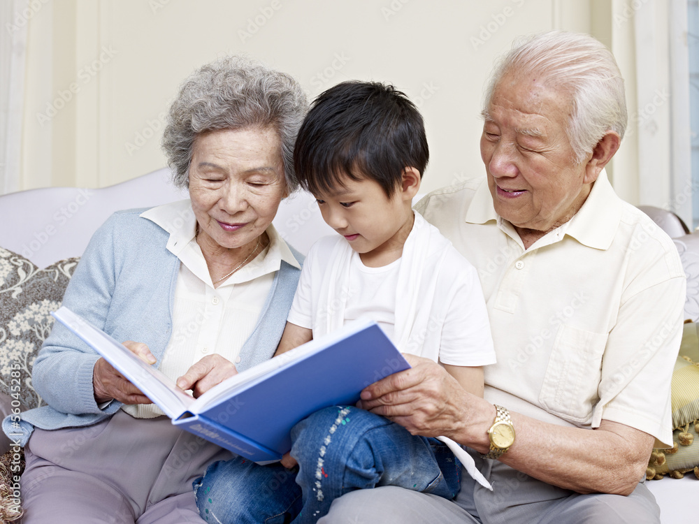 grandparents and grandson reading book together