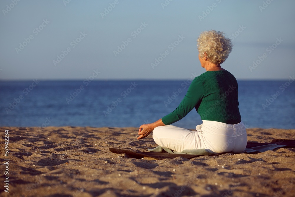 老年妇女在海滩上做瑜伽冥想