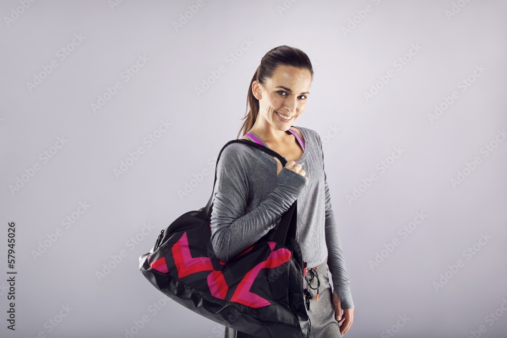 Happy fit young woman with gym bag