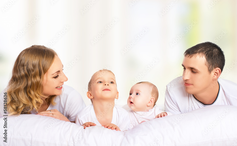 happy family of father, mother and children in white bed