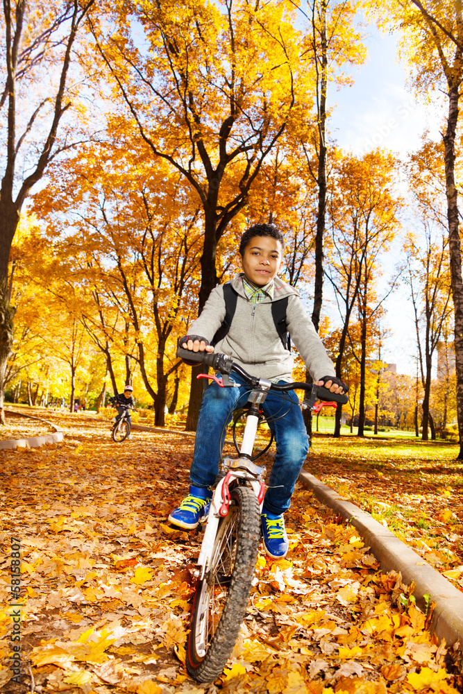 男孩在秋季公园骑行