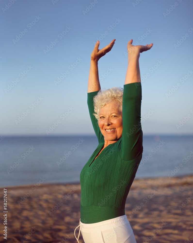 健康的老年女性在海滩上练习瑜伽