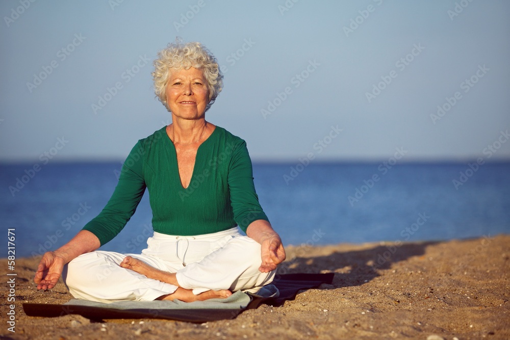 在沙滩上冥想的老年妇女