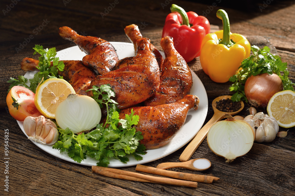 Roasted chicken with ingredients on wooden table.