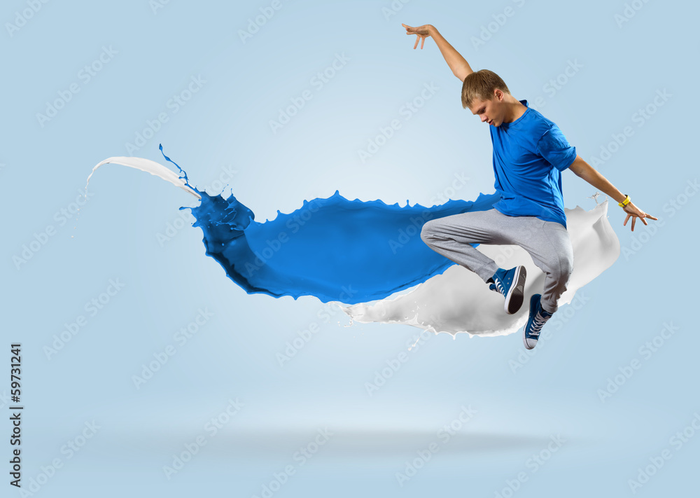 年轻的男舞者用泼溅的油漆跳跃
