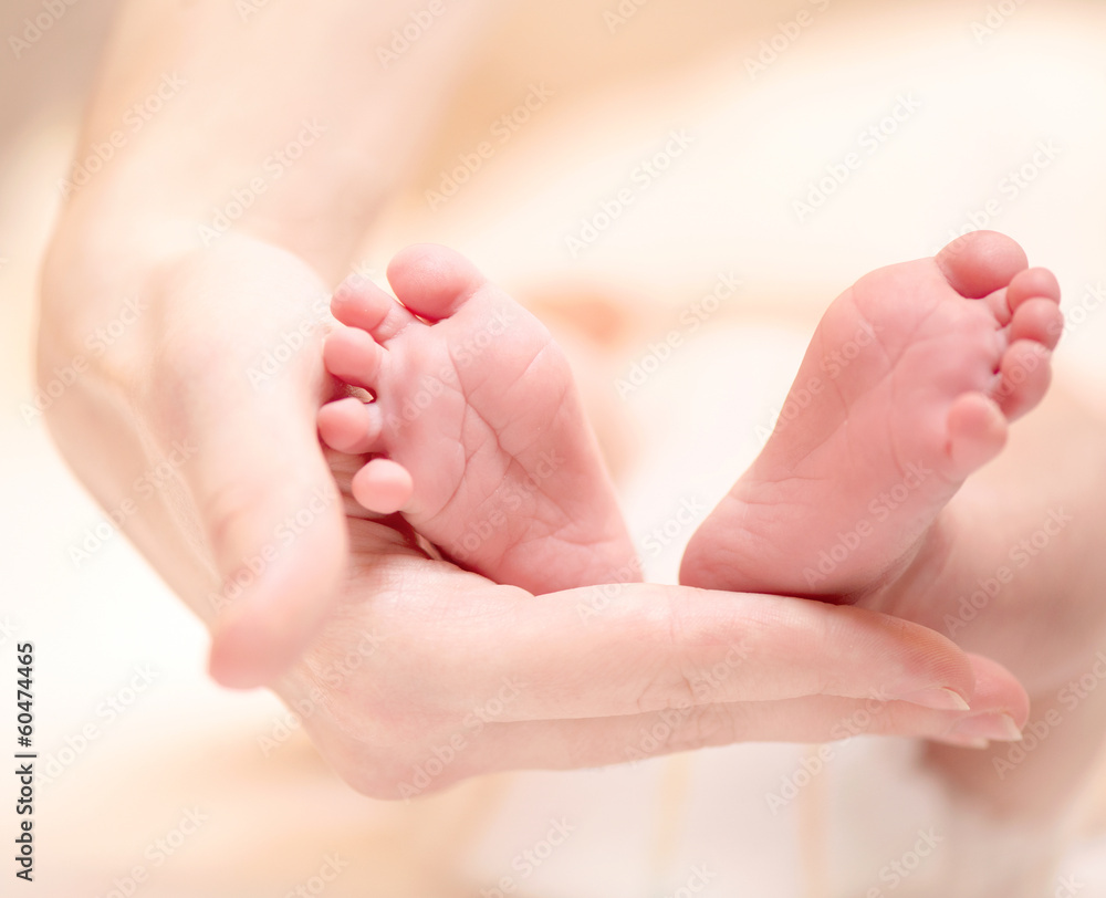 女性手上的微小新生儿脚特写。