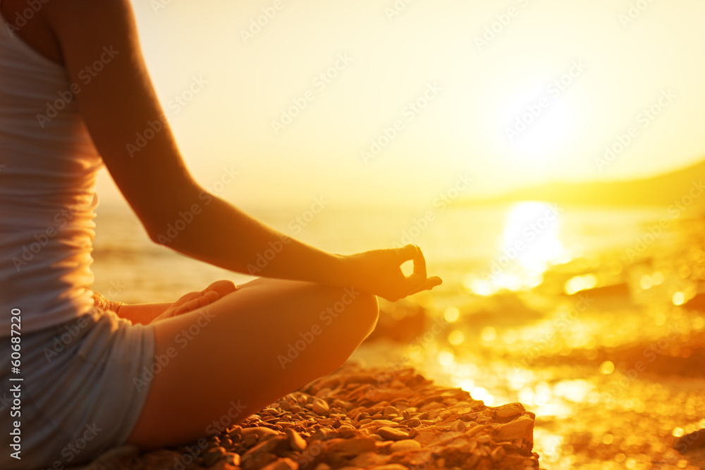 在海滩上以瑜伽姿势冥想的女人的手