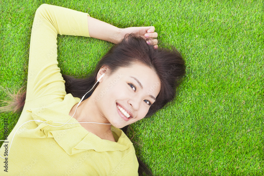 pretty woman listening music and lying on a meadow