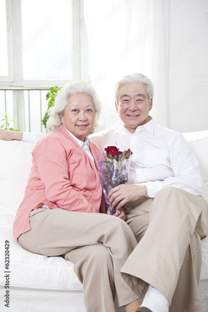 。一对老年夫妇手里拿着一束玫瑰。