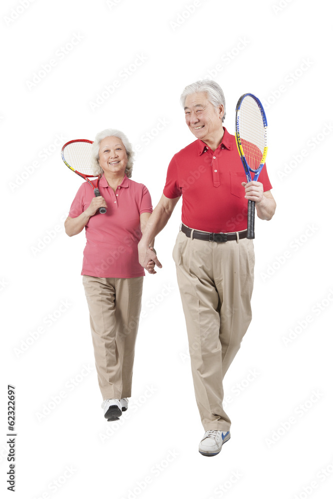 。一对老年夫妇拿着网球拍。