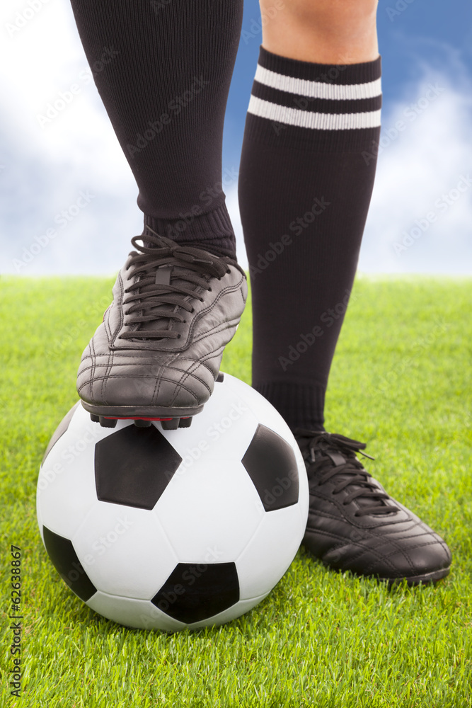 足球运动员的脚和天空背景的足球
