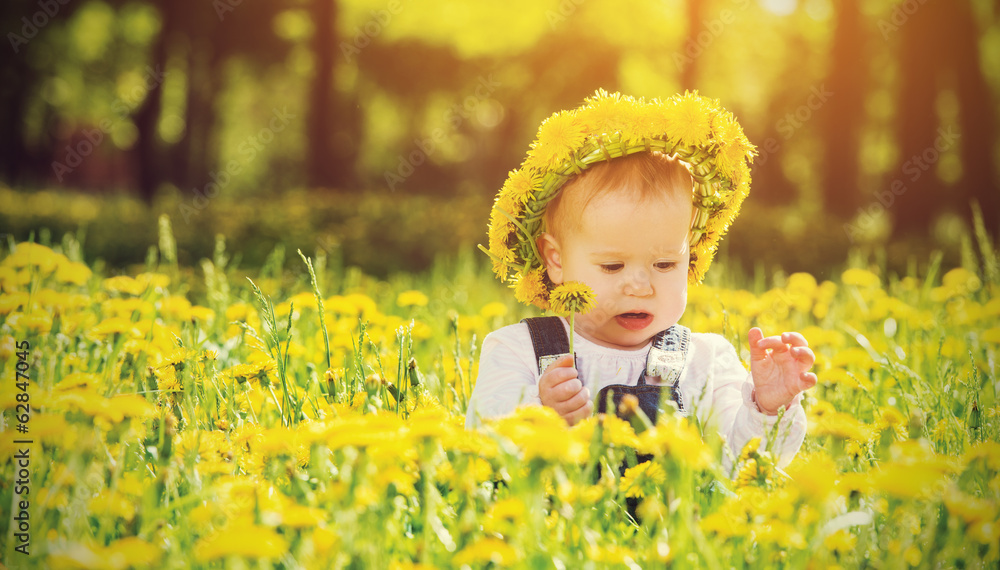 happy baby girl in a wreath on  meadow with yellow flowers  on t