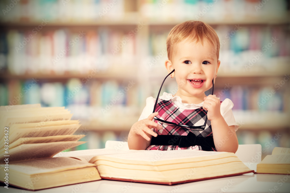 戴眼镜的有趣女婴在图书馆看书