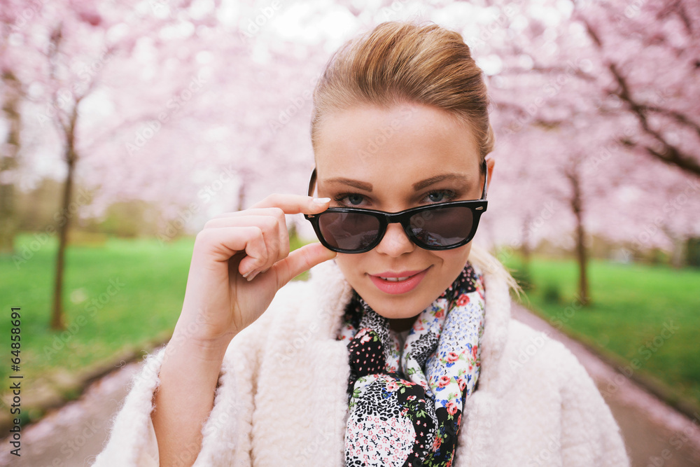 美丽的女性在春天公园戴着墨镜看
