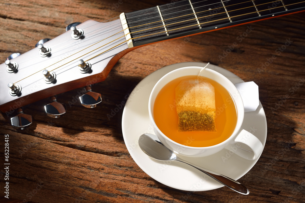 一杯茶，茶包和吉他放在木桌上