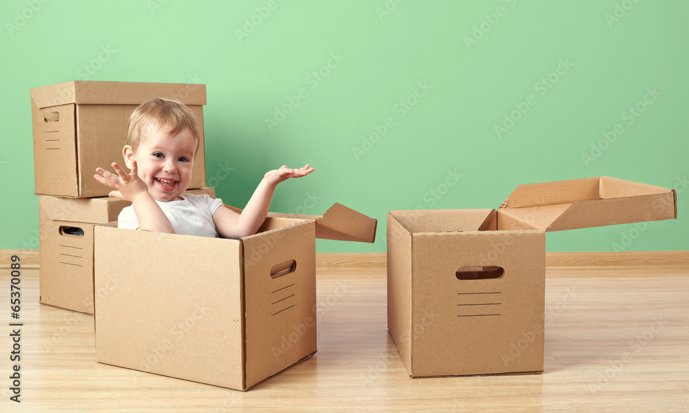 快乐的蹒跚学步的婴儿坐在纸板箱里