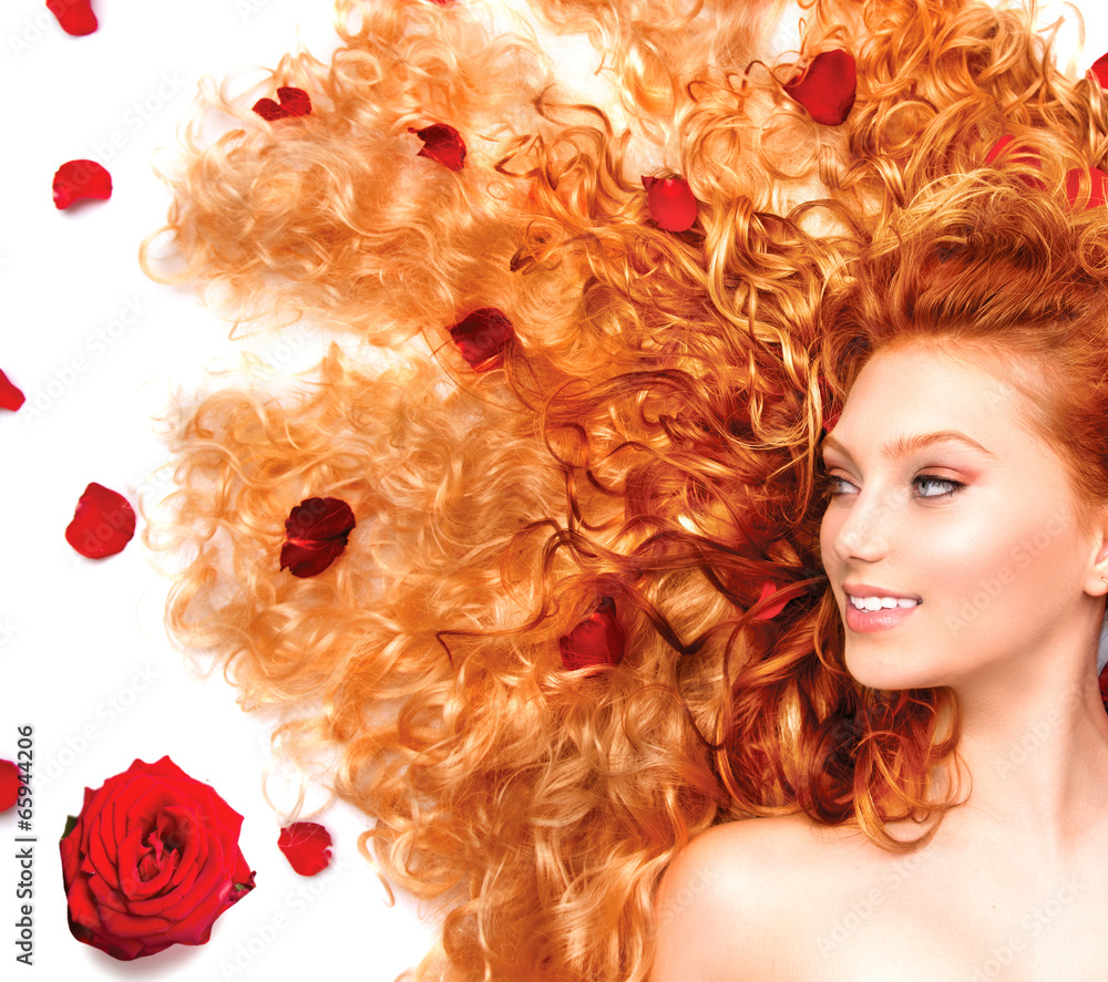 Beauty girl with long curly red hair and beautiful red roses