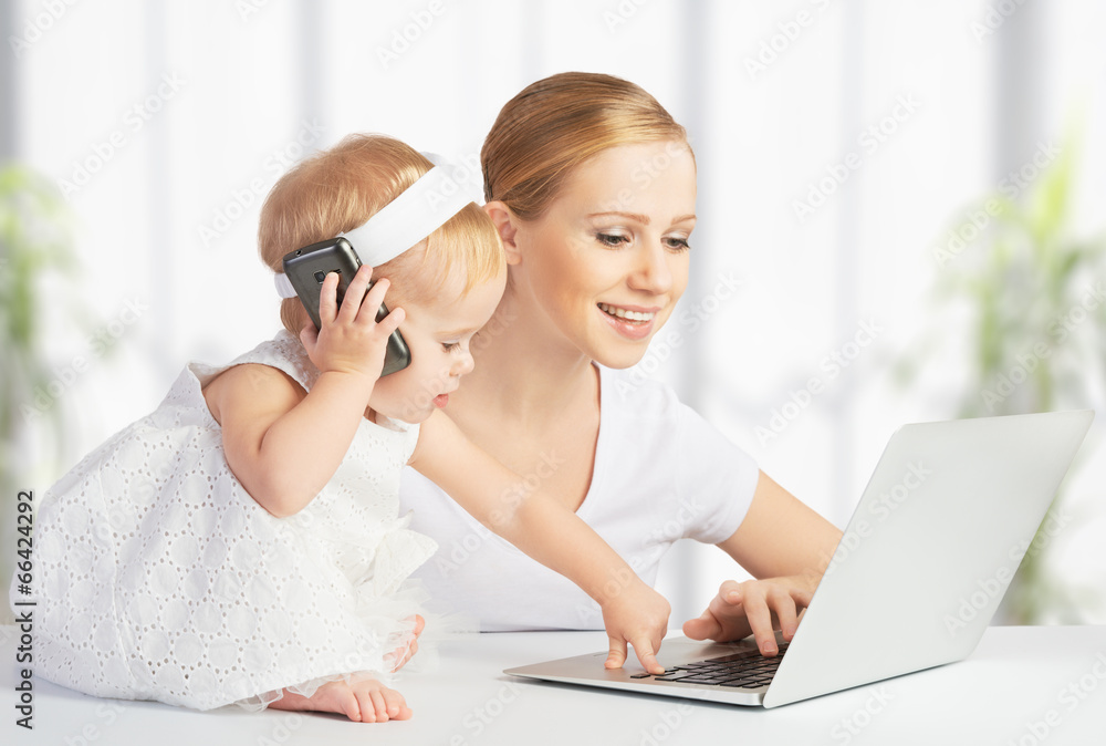 带着小女儿的母亲使用电脑和手机工作