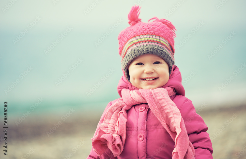 戴着粉色帽子和围巾的快乐女婴笑了