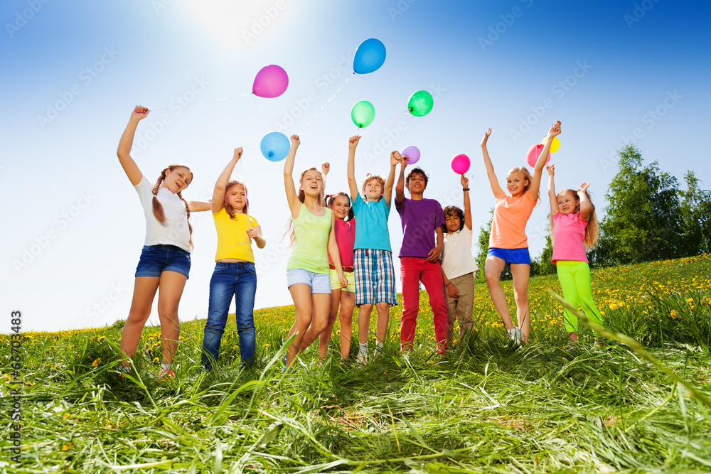 Jumping kids with flying balloons in summer