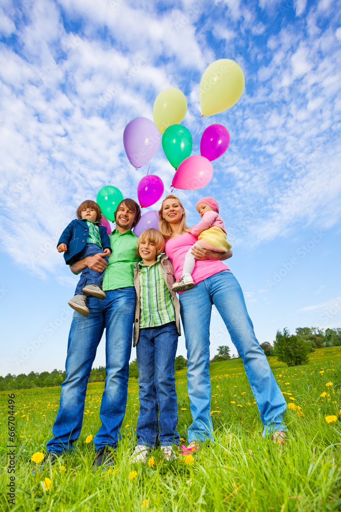 父母和孩子拿着气球站在公园里
