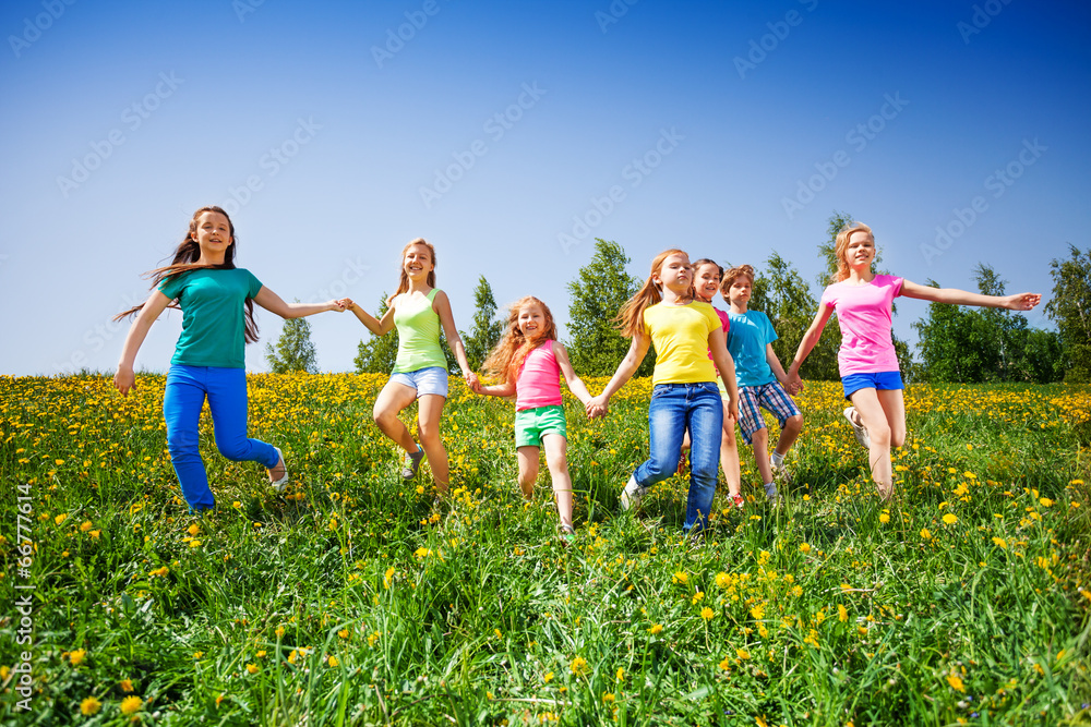快乐的孩子们在绿色的草地上奔跑并牵着手