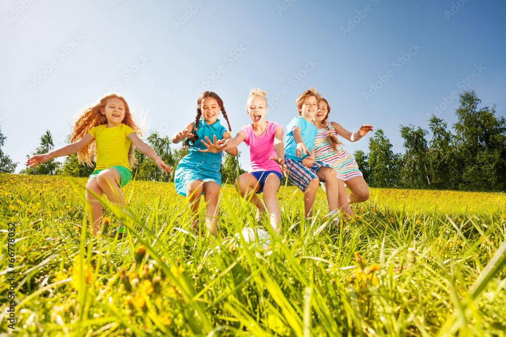 快乐的孩子们在黄色草地上踢足球