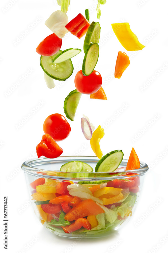 Fresh vegetables falling into the glass bowl