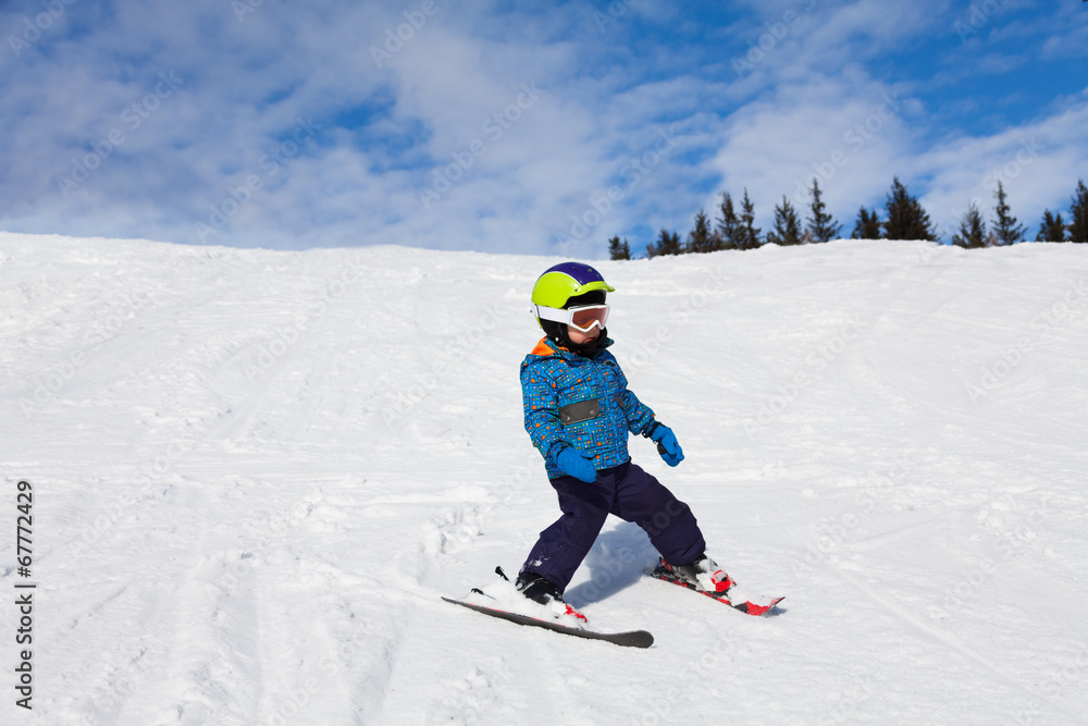 戴着滑雪面罩的男孩在雪地下坡滑雪
