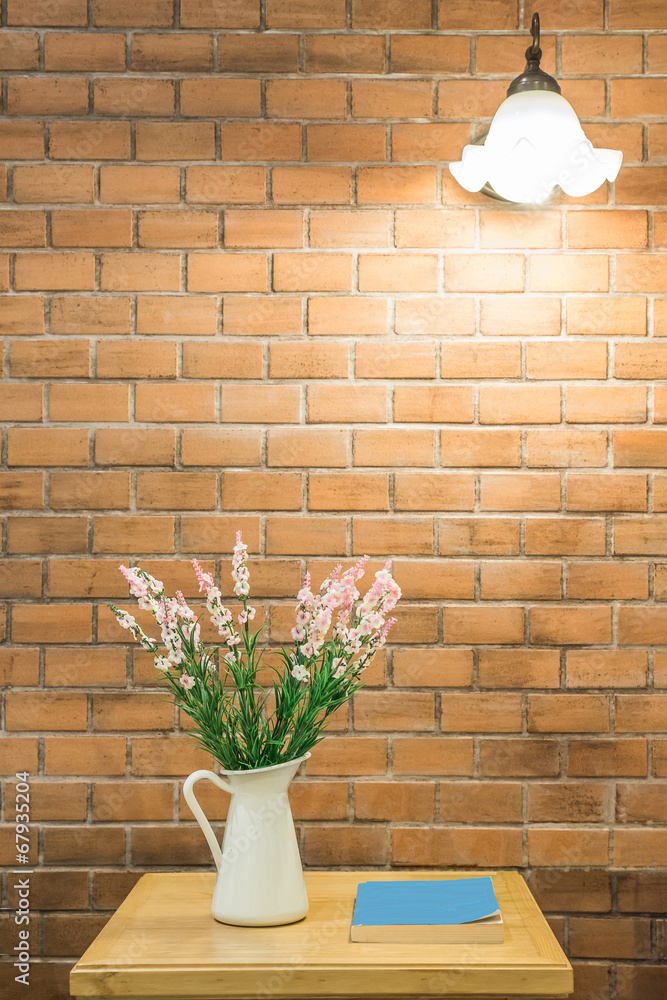 Vase of flower and book on table with light hang on wall
