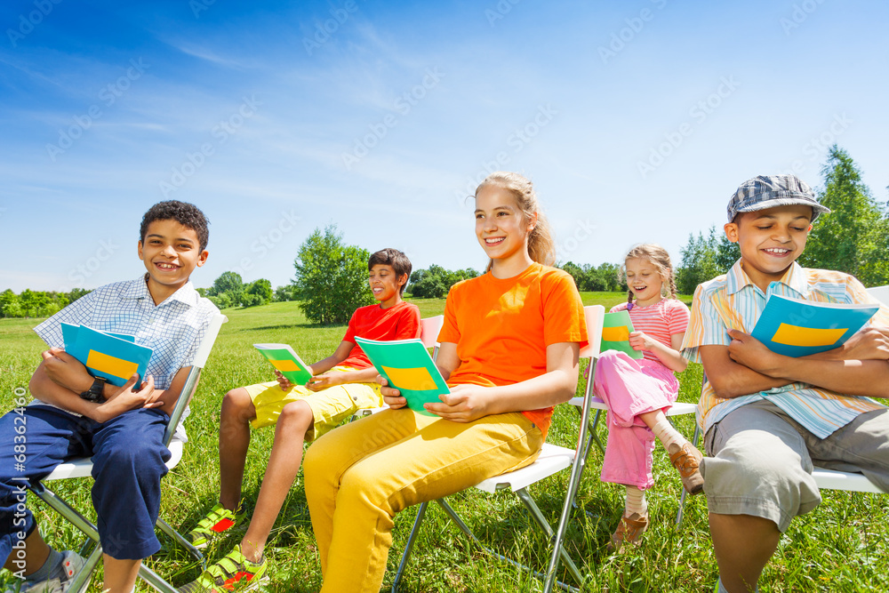 快乐的孩子拿着练习本坐在椅子上