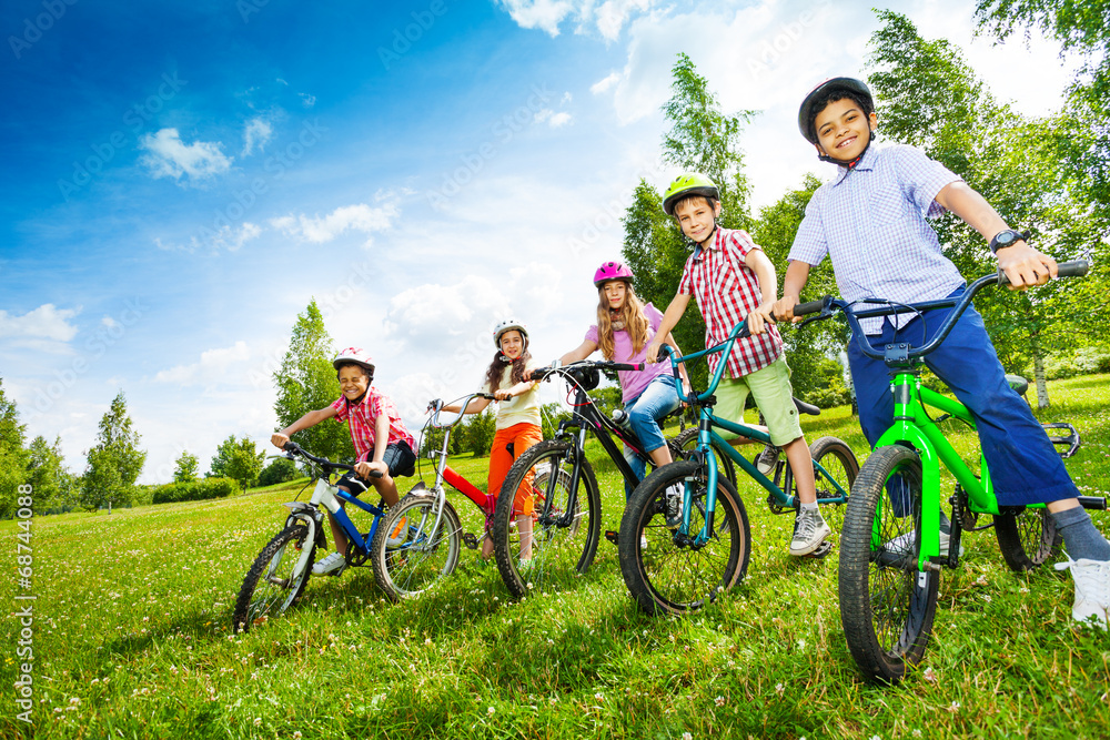 一排戴着彩色头盔、骑着自行车的孩子