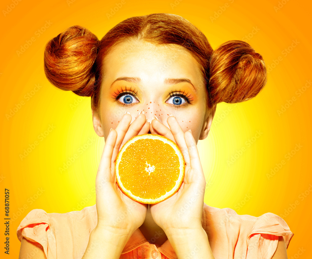 女孩吃多汁的橙子。美丽快乐的雀斑少女