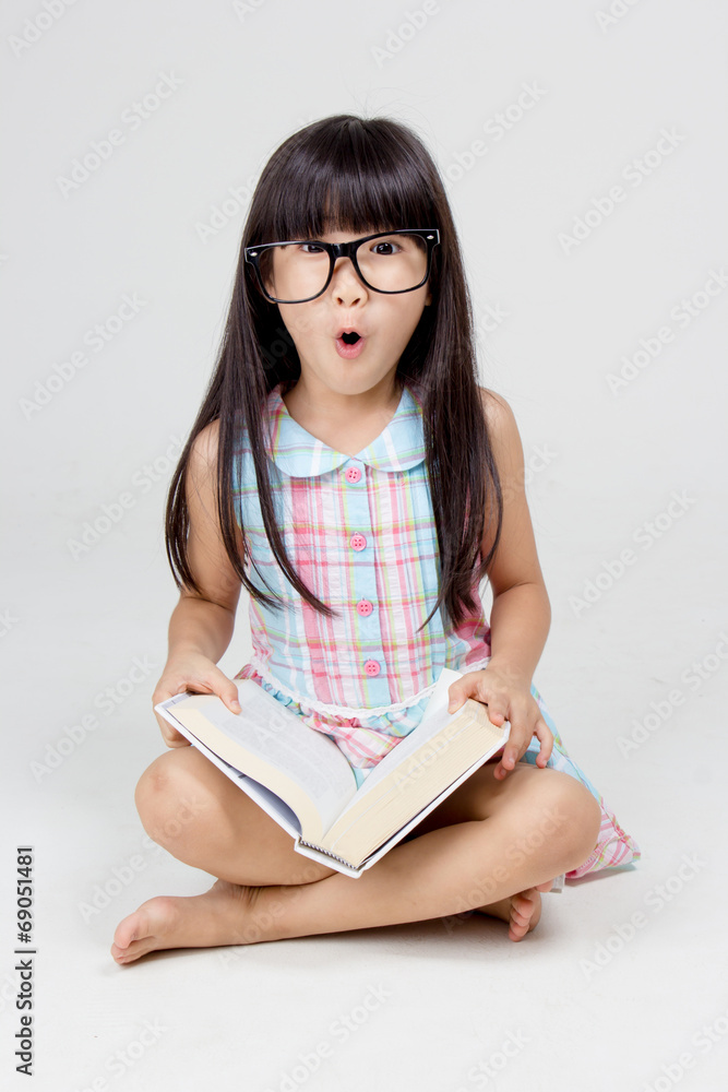 一个亚洲小孩惊讶地拿着一本书的画像