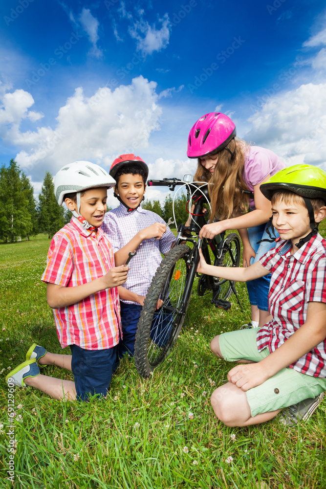 快乐的孩子戴着五颜六色的头盔修理自行车
