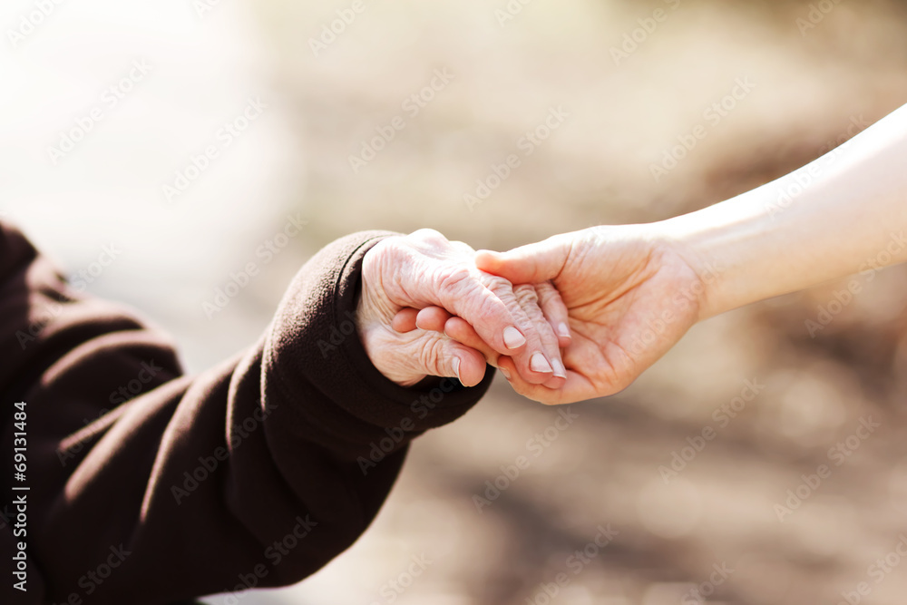 老年妇女与年轻看护人牵手