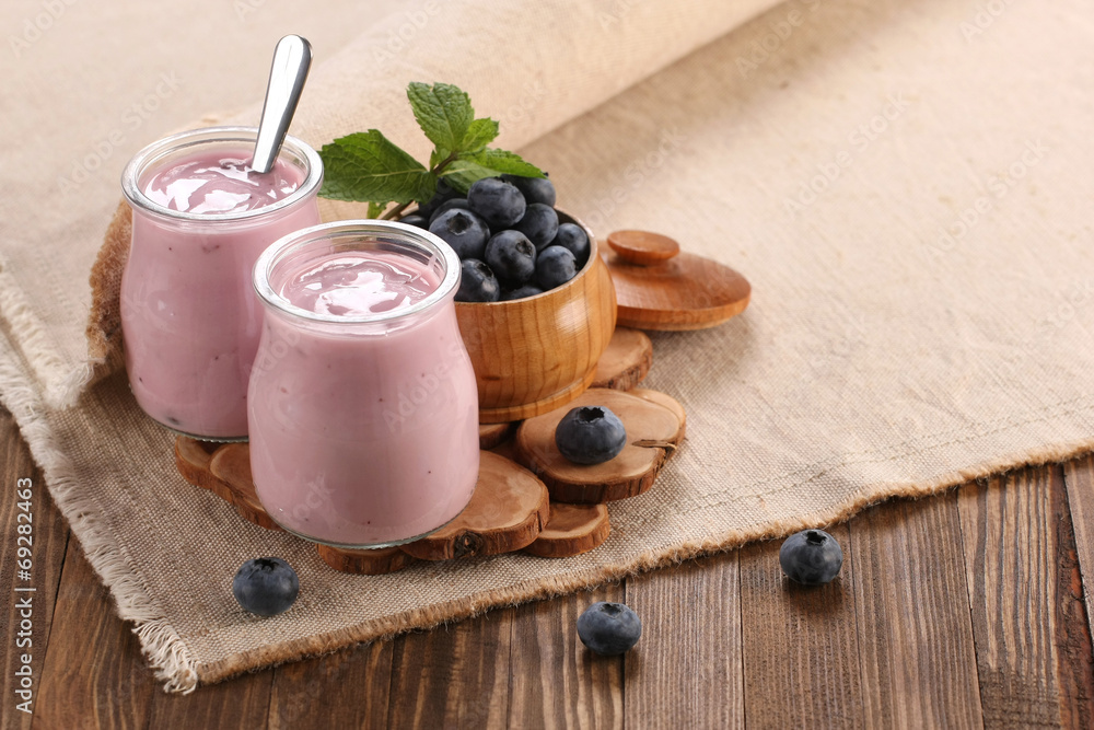 玻璃罐里有蓝莓的酸奶，木头里有蓝莓