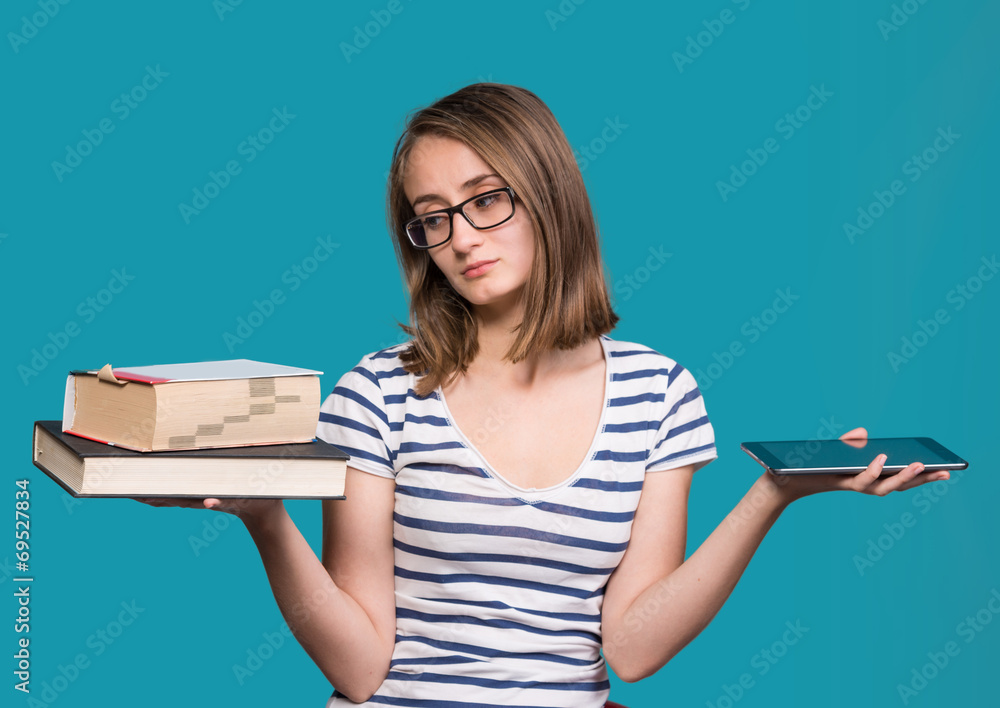 年轻女孩一手拿着一本书，另一只手拿着平板电脑