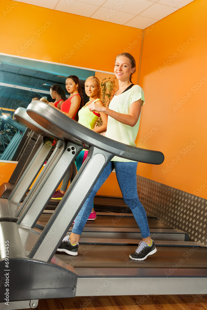 一群女孩在健身房的跑步机上跑步