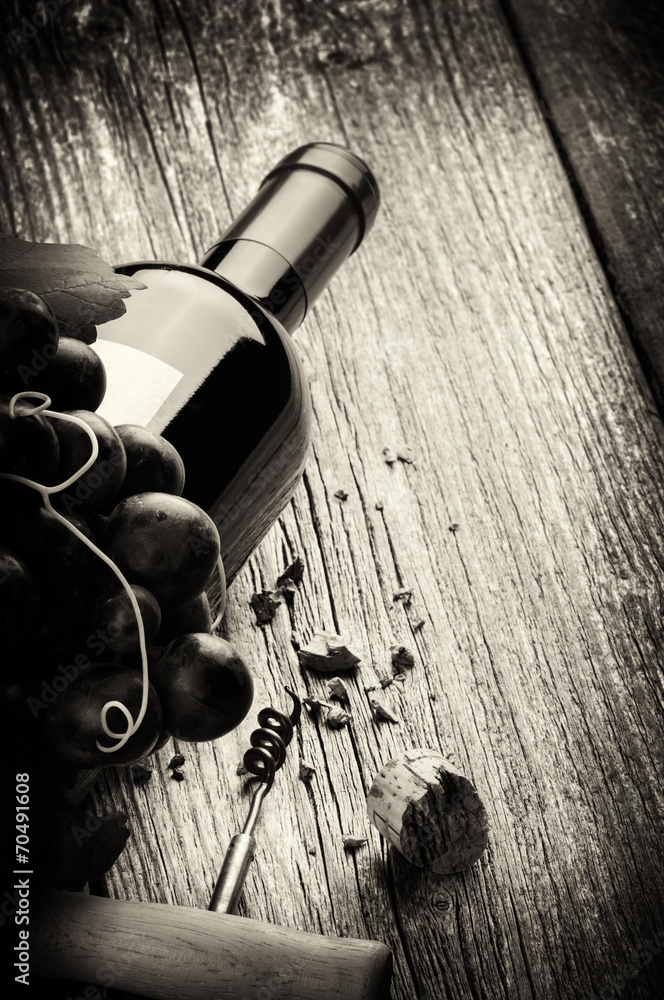 一瓶带新鲜葡萄和开瓶器的红酒