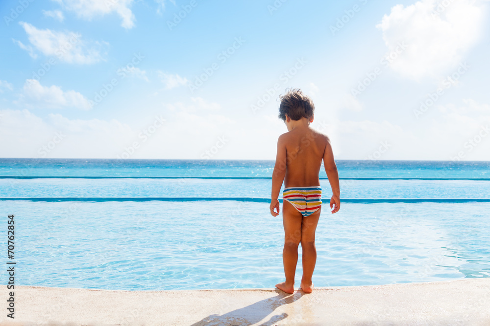 男孩站在游泳池的石板上