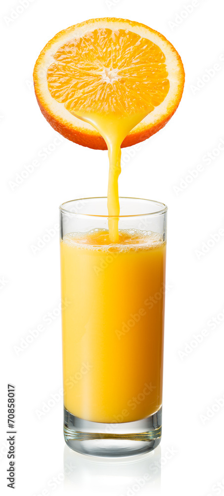 橙汁正在倒进玻璃杯。白色隔离