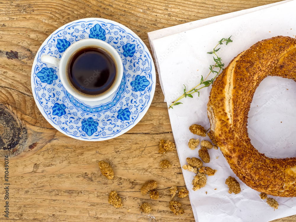 A cup of Turkish coffee and a sesame bagel on a wooden desk
