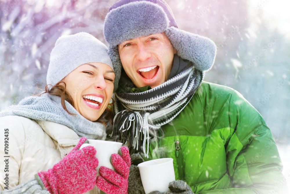 快乐的冬季情侣在户外玩得很开心。热饮
