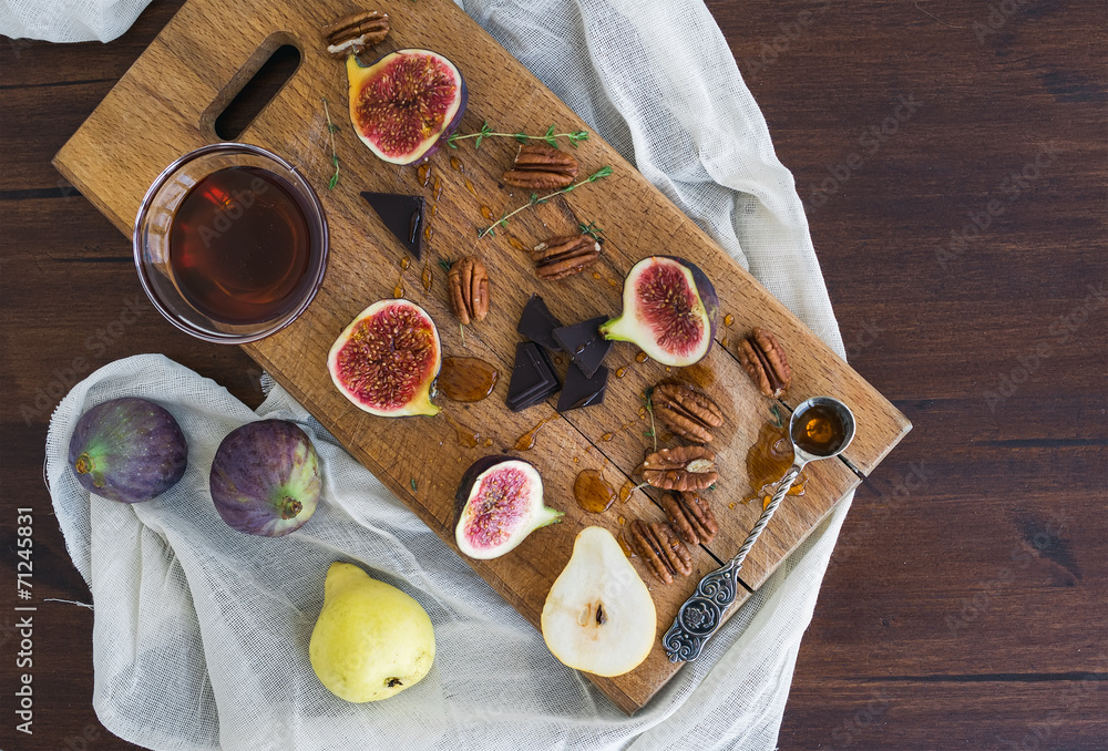 木板上的新鲜无花果、梨和带蜂蜜的pekan坚果
