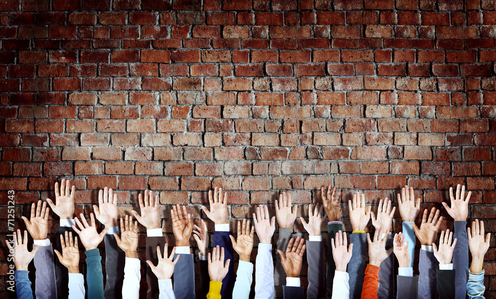 一群不同的手在砖墙上举起