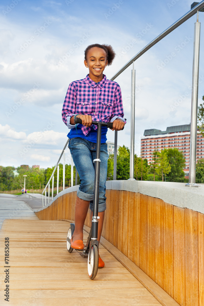 微笑的非洲女孩在夏天骑推自行车