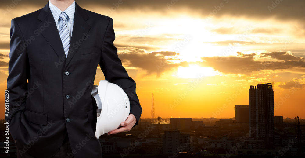 Businessman holding safety helmet with city background