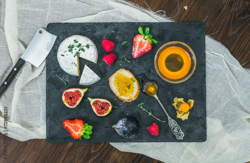 奶酪和水果放在深色石板上