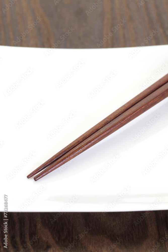 亚洲餐桌白盘子和棕色木筷子